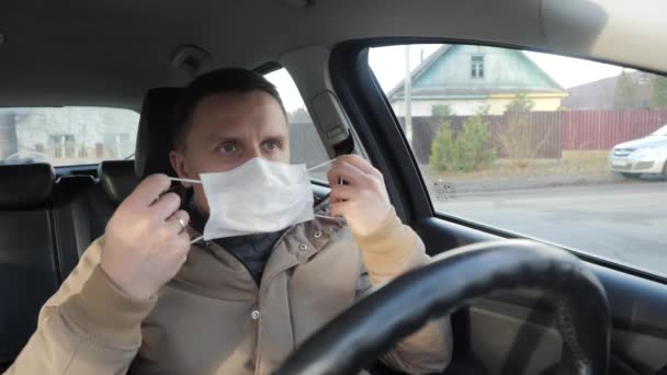 Föraren av bilen sätter på sig en medicinsk mask. — Stockvideo