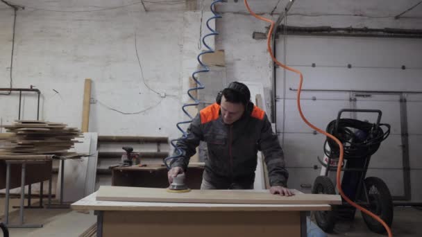 Un trabajador de la industria del mueble muele productos de madera con una amoladora. — Vídeos de Stock