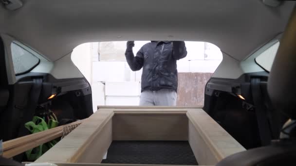 Een man haalt het aangekochte meubilair uit de auto.. — Stockvideo