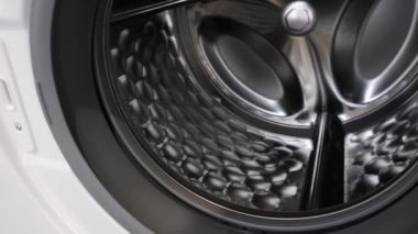 Kamera açık çamaşır makinesinde yavaşça hareket eder ve içini gösterir.
