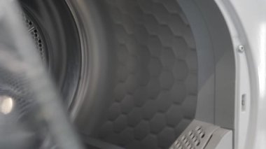 Kamera açık çamaşır makinesinde yavaşça hareket eder ve içini gösterir.