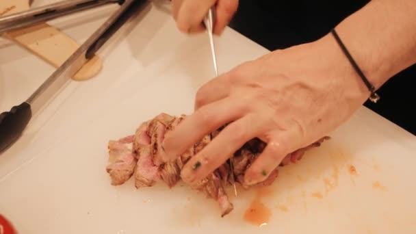 O cozinheiro corta a carne cozida em pedaços. — Vídeo de Stock