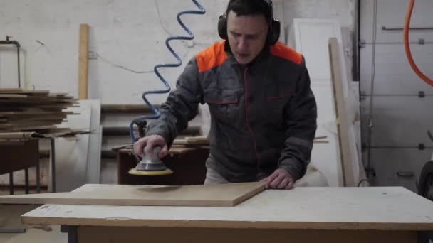 Un operaio ascolta musica e balli mentre macina il legno. — Video Stock