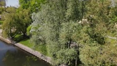 İHA parktaki ağaçların arasından uçar ve koşan atleti takip eder.