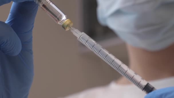 Ein Arzt wählt den Impfstoff aus einer Ampulle in eine Spritze — Stockvideo