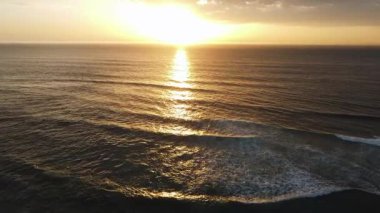 Gün batımı okyanus ufku, dalgalanan suyun altın yansıması, sıcak ve sakin dalgalar, sinematik hava
