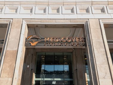 SAVAŞ, POLAND - 22 HAZİRAN 2026 Medicover Stomatoloji diş sağlığı kliniğinin Anayasa Meydanı 'ndaki tarihi bir binanın ön cephesindeki logosu ve tabelaları