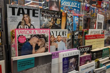 WARA, POLAND - 5 Ocak 2026: Pop kültürü, müzik ve oyun dergilerinin yer aldığı bir basın mağazasında sergi rafı. Önemli kapaklar arasında Taylor Swift ve Travis Kelce, Tate McRae ve Game Boy X gibi oyun başlıklarına adanmış özel basımlar yer alıyor.