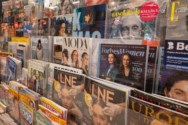 WARA, POLAND - 5 Ocak 2026: Çeşitli iş ve yaşam tarzı dergilerinin yer aldığı bir basın mağazasında sergi rafı. Önemli başlıklar arasında Forbes Women with the Women 100 'ün Polonya baskısı, LNE ve Moda w Polsce yer alıyor.