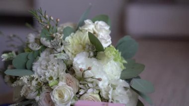 Yeşil okaliptüs yapraklı zarif beyaz ve krema çiçekleri, narin ve romantik bir şekilde yerleştirilmiş, yumuşak bulanık bir arka planla kapalı bir yere yerleştirilmiş.