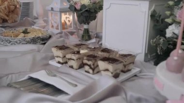 Bireysel tiramisu fincanları, katmanlı gofret kurabiyeleri ve mum, çiçek ve yumuşak kumaş gibi dekoratif elementlerin yer aldığı zarif bir tatlı masası, lüks ve romantik bir atmosfer yaratıyor.