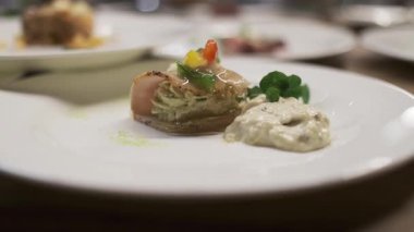 Gurme aperatifler zarif tabakta, kremalı rulo et, renkli sebzeler, otlar ve sosla süslenmiş, rafine edilmiş yemekler ve sofistike mutfak sunumuyla sunuluyor.