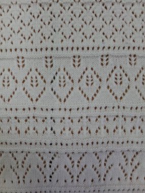 Elmas ve yay şeklinde dizilmiş küçük koyu noktalardan oluşan tekrarlayan geometrik deseni içeren bir kumaş veya yüzeye yakın çekim görüntüsü