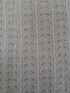 Yumuşak, sessiz renkler ve belirgin desenli bir yüzey ile tekrarlayan bir deseni içeren dokuma tekstilin ayrıntılı bir görüntüsü