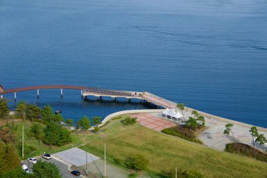 Geoje Adası 'ndaki derin mavi körfezin yanına uzanan Jisepo Limanı' ndaki kıvrımlı bir rıhtım ve iskele, manzaranın keyfini çıkaran birkaç aylak ile birlikte..