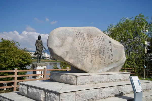 Chuncheon 'daki Uiam Gölü' nün karşısındaki köprünün yanında stilize bir balık heykeli yükseliyor, Soyang Nehri koridoru boyunca apartman blokları ve eteklere karşı kuruluyor..