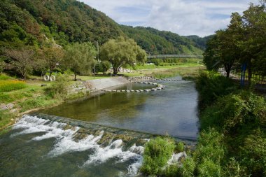 Basamaklar, Gangchon 'da nehir kenarındaki bir parkta söğütlerin ve çimenlerin altındaki sığ bir akarsu boyunca kıvrılır..