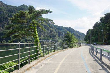 Samaksan yakınlarındaki ormanlık kayalıkların altında Uiam Gölü boyunca bir nehir kenarı bisiklet yolu kıvrımlı, korkulukları ve boyalı merkeziyle kayalara doğru giden bir göl kenarı galerisi var..