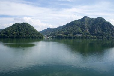 Yuvarlak, ağaçlarla kaplı bir ada, Samaksan 'ın kayalık yamaçlarının karşısındaki Uiam Gölü' nden yükseliyor, durgun su ve katmanlı tepeler vadiyi simetrik bir şekilde gösteriyor..