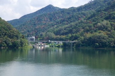 Uiam Gölü 'ndeki Uiam Barajı' nın yakınlarındaki ormanlık tepelerin altında bir nehir kenarı ve küçük binalar bulunur. Vadinin daraldığı ve yansımalarının yeşil sularda dalgalandığı yer..