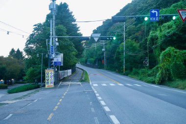 Namyangju 'da sakin bir tepe yolu ayrık bir bisiklet yolunun yanından geçer ve elektrik hatları birbirine dolanır. Yeşil ışıklar ve yol kenarındaki ağaçlar Buhangang rıhtımına kadar uzanır..