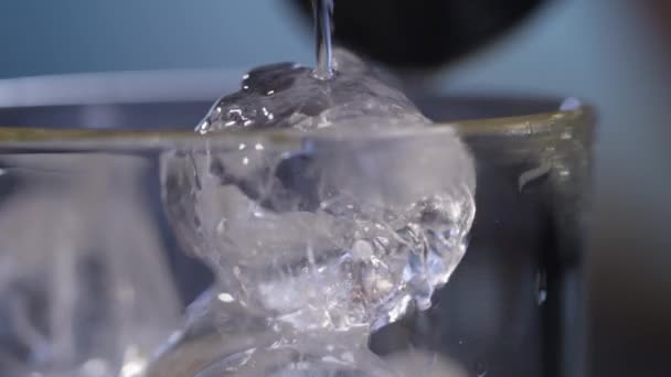 Water pouring over ice in glass — Stock Video