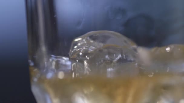 Closeup of whiskey pouring over ice in glass — Stock Video