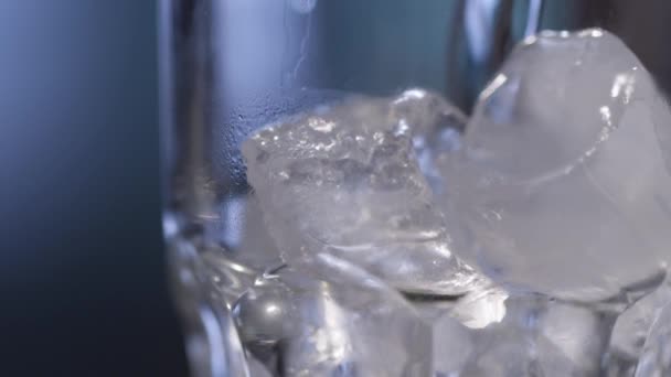 Νερό ρίχνει πάνω από πάγο σε ποτήρι — Αρχείο Βίντεο