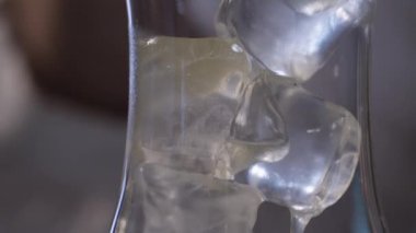 Bir bardak buz üzerinde akan sarı sıvı 