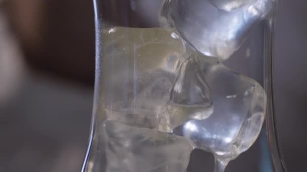 Gelbe Flüssigkeit fließt auf Eis im Glas — Stockvideo