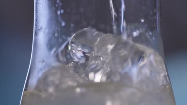 Líquido que fluye sobre hielo en un vaso — Vídeos de Stock