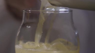 Bir bardak buz üzerinde akan sarı sıvı 