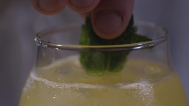 Lägga till en mint i gul cocktail — Stockvideo