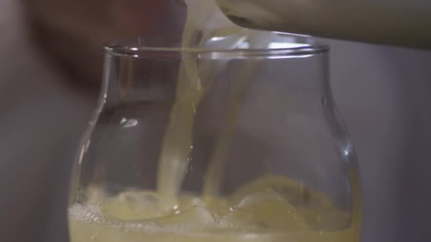 Liquide jaune coulant sur la glace dans un verre  