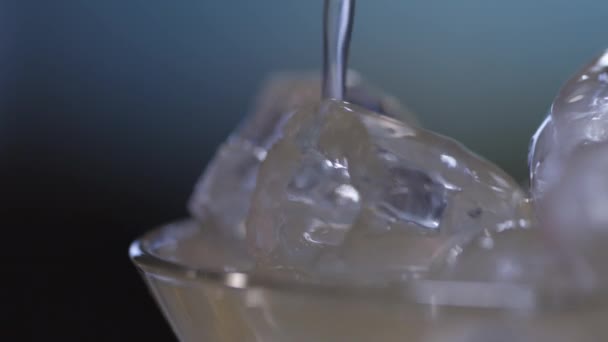 Primer plano del líquido que fluye sobre el hielo en un vaso — Vídeos de Stock