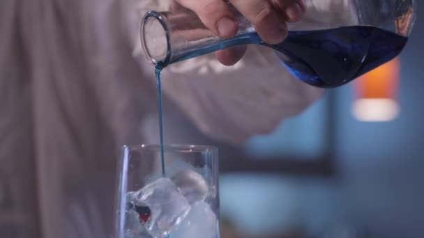 Blaue Flüssigkeit mit Eis ins Glas geben — Stockvideo