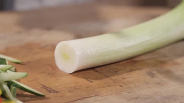 Крупним планом ріжучий цибулю-порей на обробній дошці — стокове відео
