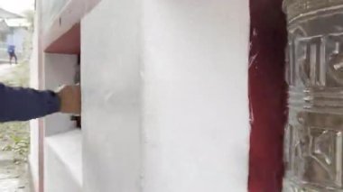 Nepal 'de bir Budist dua çarkının ve renkli dua bayraklarının sinematik 4K manzaralı çekimi. Tibet ruhani atmosferi, kutsal semboller, meditasyon, Himalayalar, ilahi ve huzurlu ruh hali..