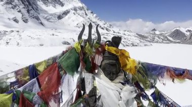 Nepal 'de bir Budist dua çarkının ve renkli dua bayraklarının sinematik 4K manzaralı çekimi. Tibet ruhani atmosferi, kutsal semboller, meditasyon, Himalayalar, ilahi ve huzurlu ruh hali..