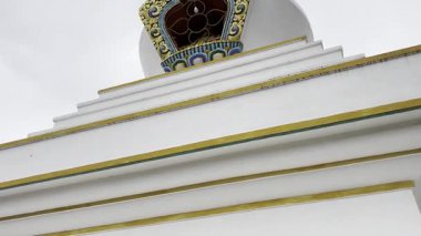 Nepal 'de bir Budist dua çarkının ve renkli dua bayraklarının sinematik 4K manzaralı çekimi. Tibet ruhani atmosferi, kutsal semboller, meditasyon, Himalayalar, ilahi ve huzurlu ruh hali..