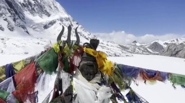 Nepal 'de bir Budist dua çarkının ve renkli dua bayraklarının sinematik 4K manzaralı çekimi. Tibet ruhani atmosferi, kutsal semboller, meditasyon, Himalayalar, ilahi ve huzurlu ruh hali..