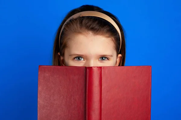 Pequeno leitor de livros se esconde atrás do livro didático, tem expressão alegre — Fotografia de Stock