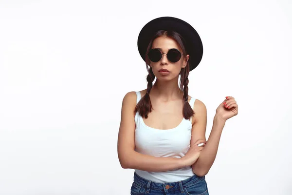 Stylish young girl in white shirt with sunglasses posing over white wall — Stock Photo, Image