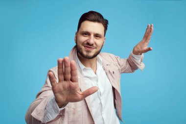 Yakışıklı, neşeli, şık elbiseli, mavi arka planda mutlu bir şekilde dans eden çocuk.