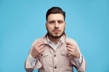 Adamın ciddi bir yüz ifadesi var. Mavi stüdyo geçmişine karşı duruyor.