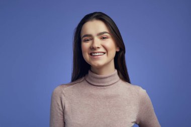 Genç ve çekici bir kız kameraya bakıyor neşeli ve büyüleyici bir gülümsemeyle