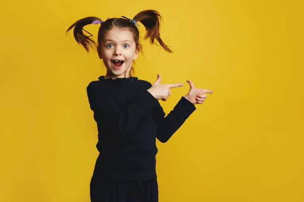 Menina sorrindo e apontando para a direita com as duas mãos enquanto salta — Fotografia de Stock