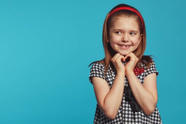 Keyifli kız sağa bakıyor, gülümsüyor ve el kol hareketi yapıyor.