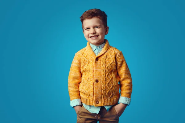 Dítě se usmívá, zatímco drží ruce v kapsách, izolované přes modré pozadí — Stock fotografie