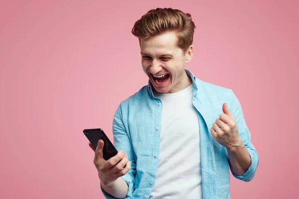 Ο άνθρωπος δείχνει χτύπημα γροθιά χαρούμενα, χρησιμοποιεί κινητό τηλέφωνο, λαμβάνει φανταστικά νέα — Φωτογραφία Αρχείου